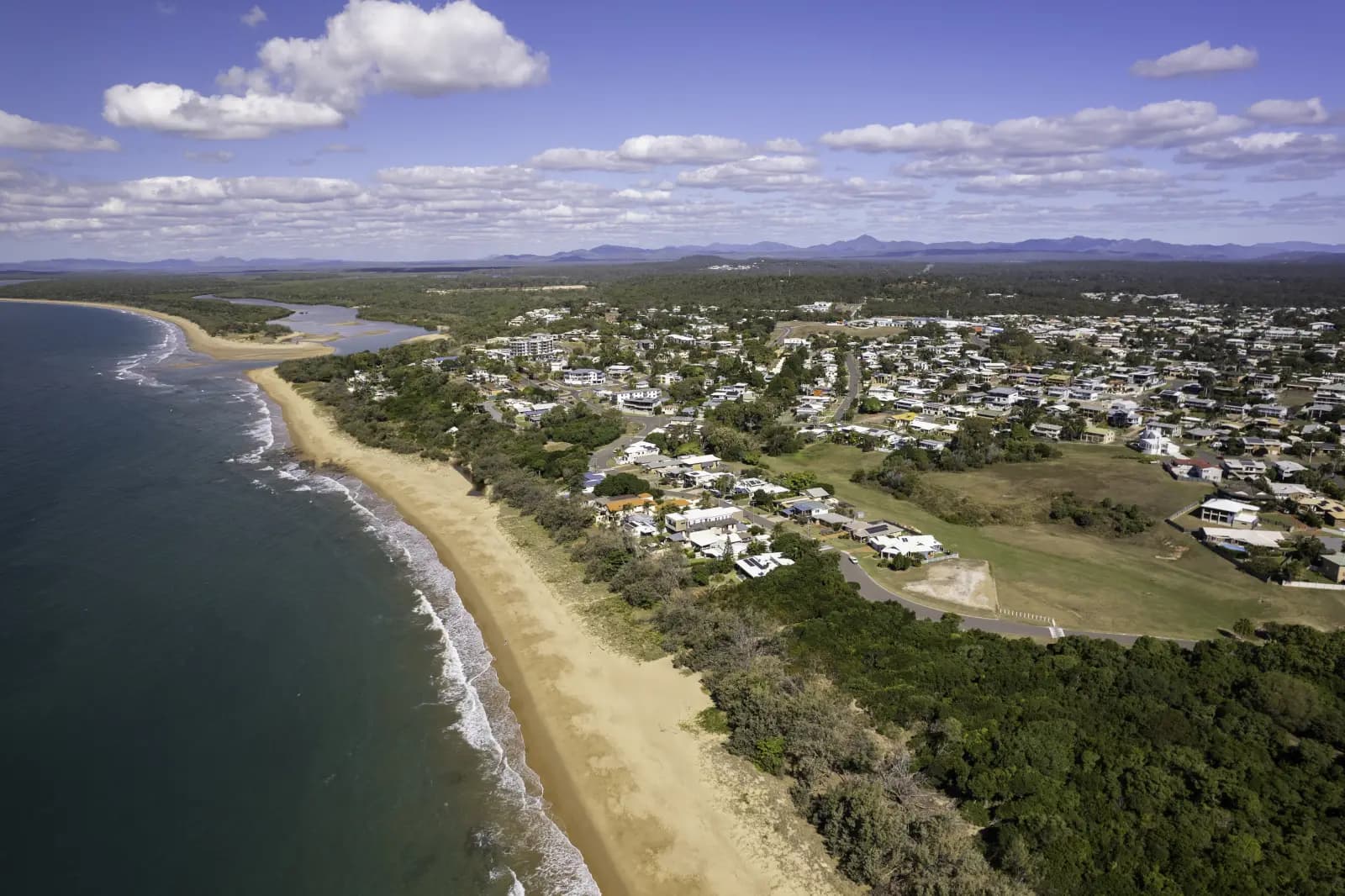 Aerial view of the long sandy beach and coastal homes at Tannum Sands